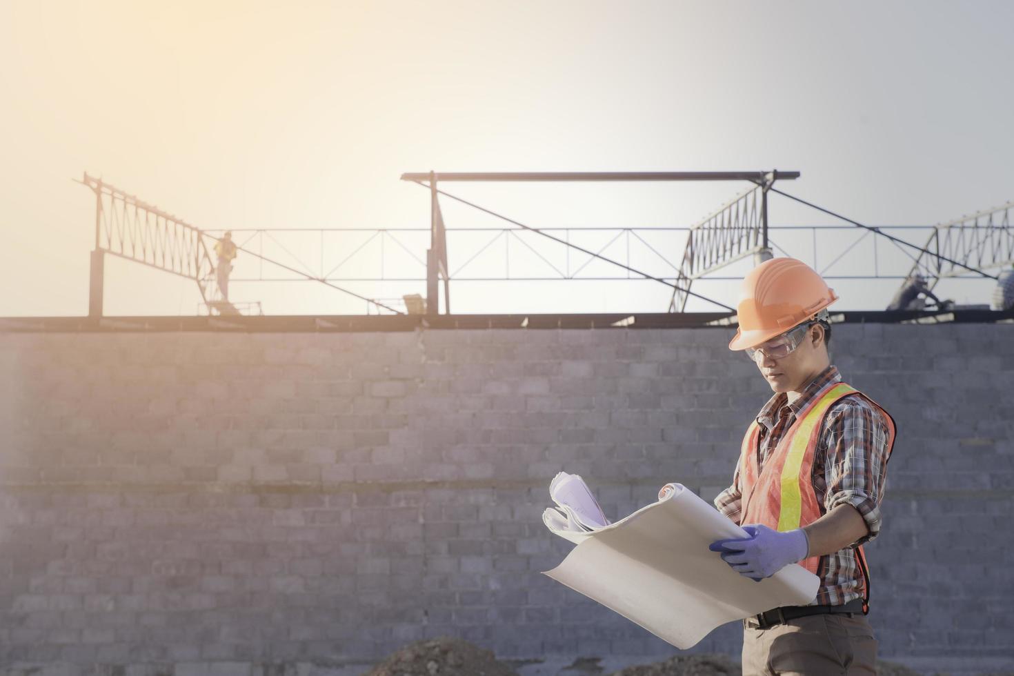 lavoratore con sicurezza veste e sicurezza casco hold il blu Stampa Lavorando a luogo linea , nuovo costruzione design e revisione processi foto