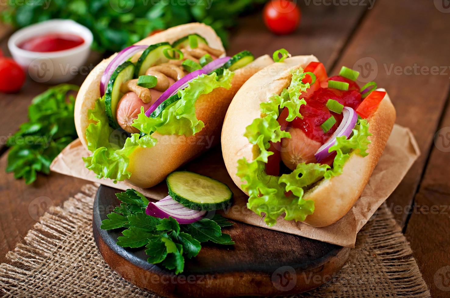 hot dog con ketchup, senape, lattuga e verdure sul tavolo di legno foto