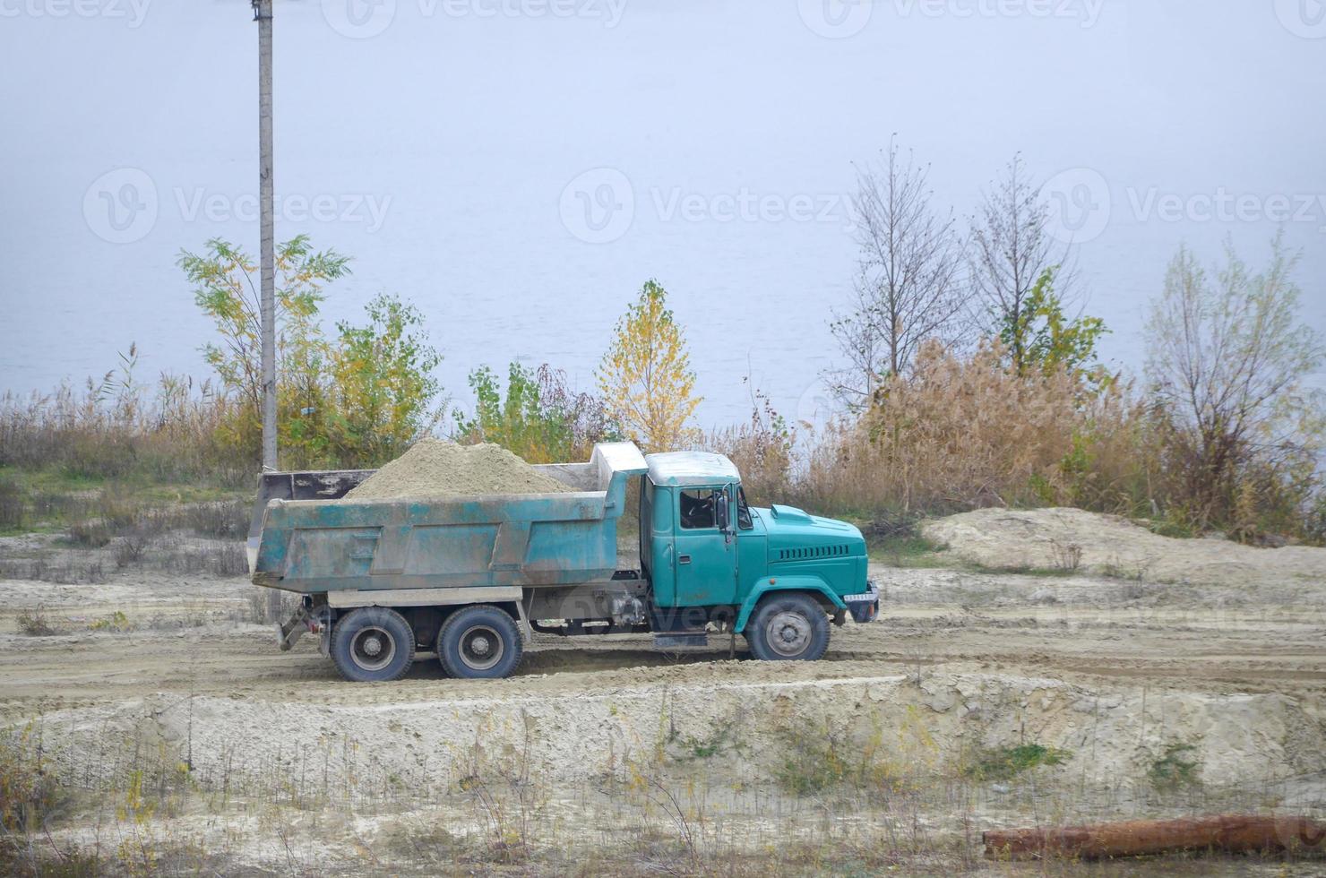 cumulo di rifiuti camion trasporti sabbia e altro minerali nel il estrazione cava. pesante industria foto