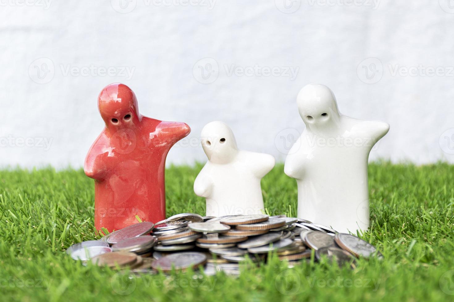 finto su famiglia statua e monete su erba pavimento con bianca sfondo foto