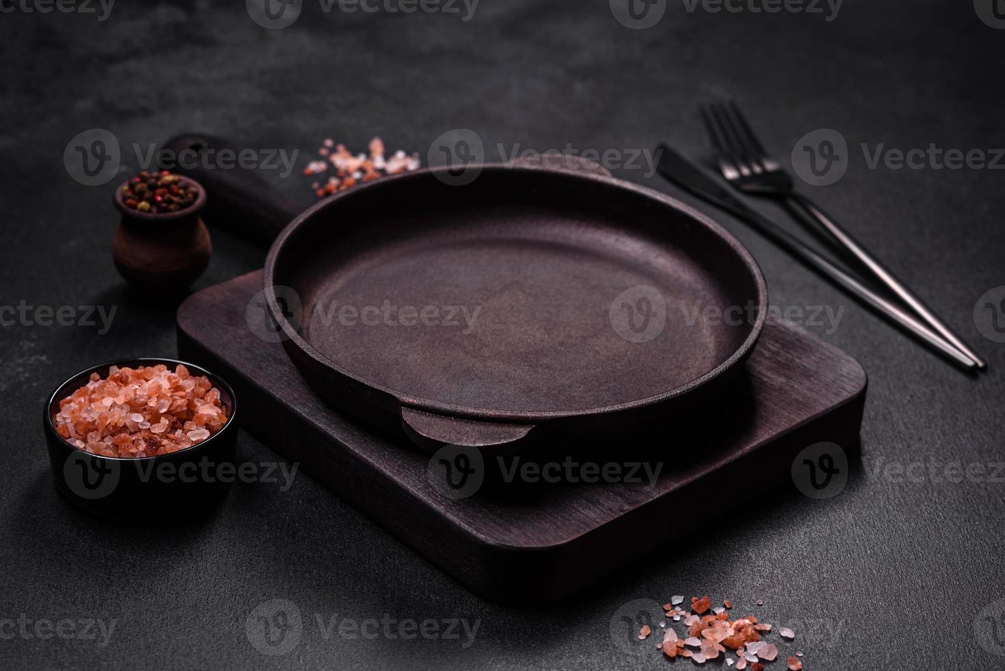 Marrone ferro vuoto padella con cucina utensili su un' buio calcestruzzo sfondo foto