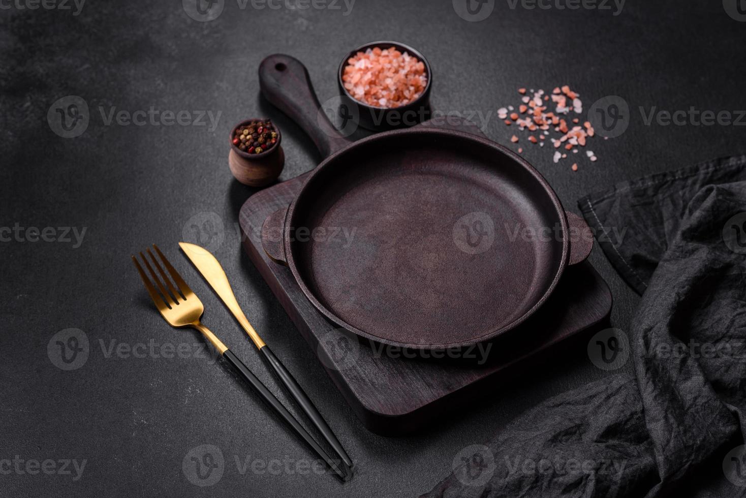 Marrone ferro vuoto padella con cucina utensili su un' buio calcestruzzo sfondo foto