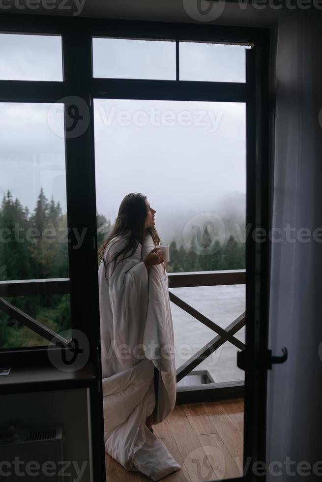 donna potabile tè su accogliente balcone di un' nazione Casa. foto
