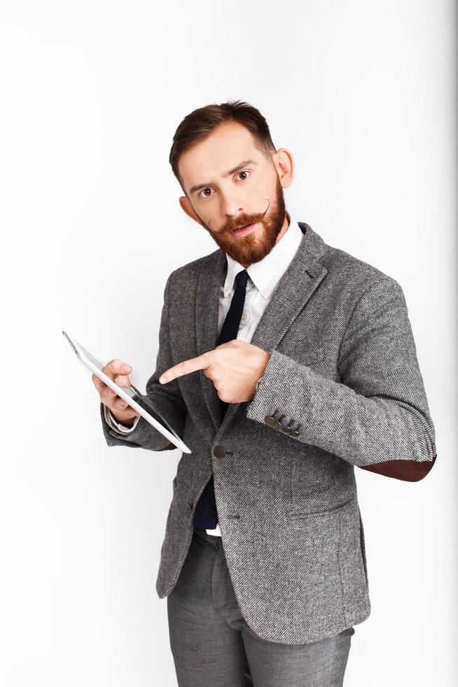 l'uomo barbuto in abito grigio indica il suo tablet foto