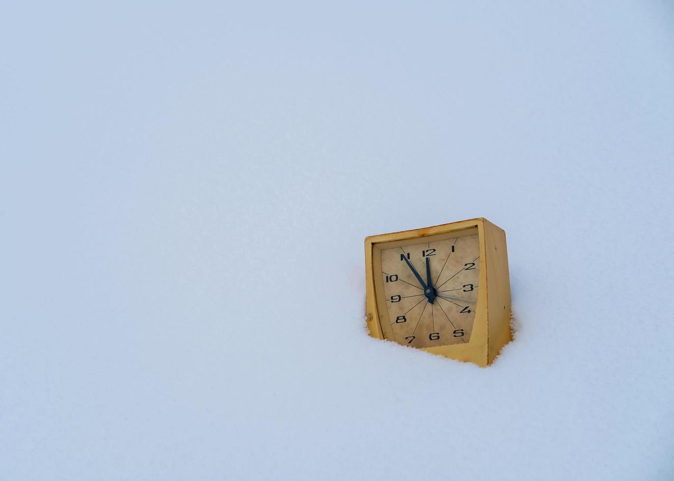 vecchio meccanico allarme orologio nel un' cumulo di neve. conto alla rovescia per mezzanotte. Natale e nuovo anni inizio concetto. copia spazio. foto