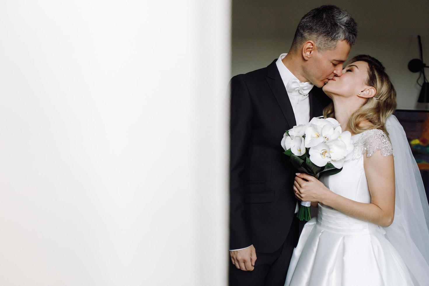 lo sposo bacia la sposa in una camera d'albergo foto