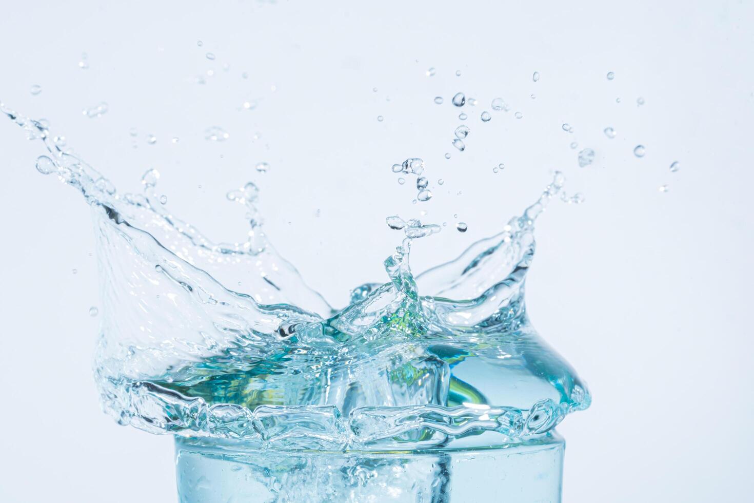 spruzzi d'acqua in un bicchiere su sfondo bianco foto