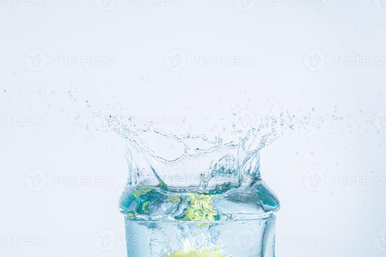 acqua spruzzata di un limone in un bicchiere foto