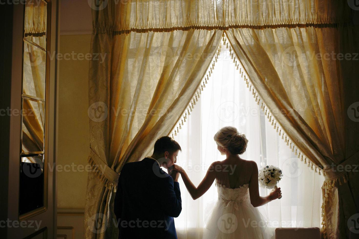 sposa e sposo in piedi nel davanti di finestra foto