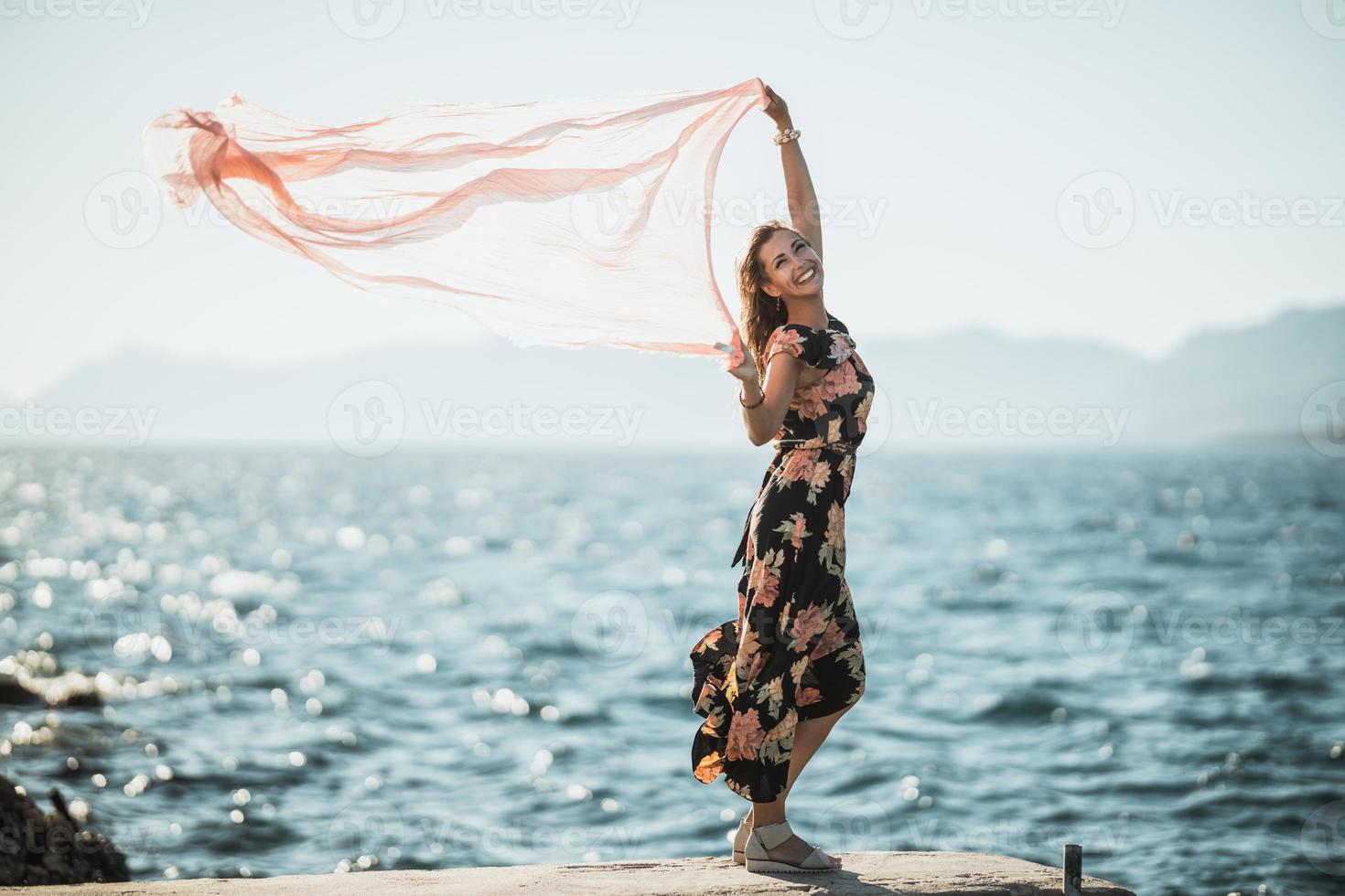 donna con sciarpa è avendo divertimento a il estate giorno su il riva del mare foto