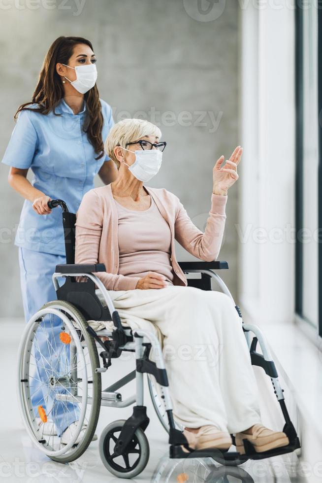 giovane badante cura un' anziano femmina in sedia a rotelle paziente foto