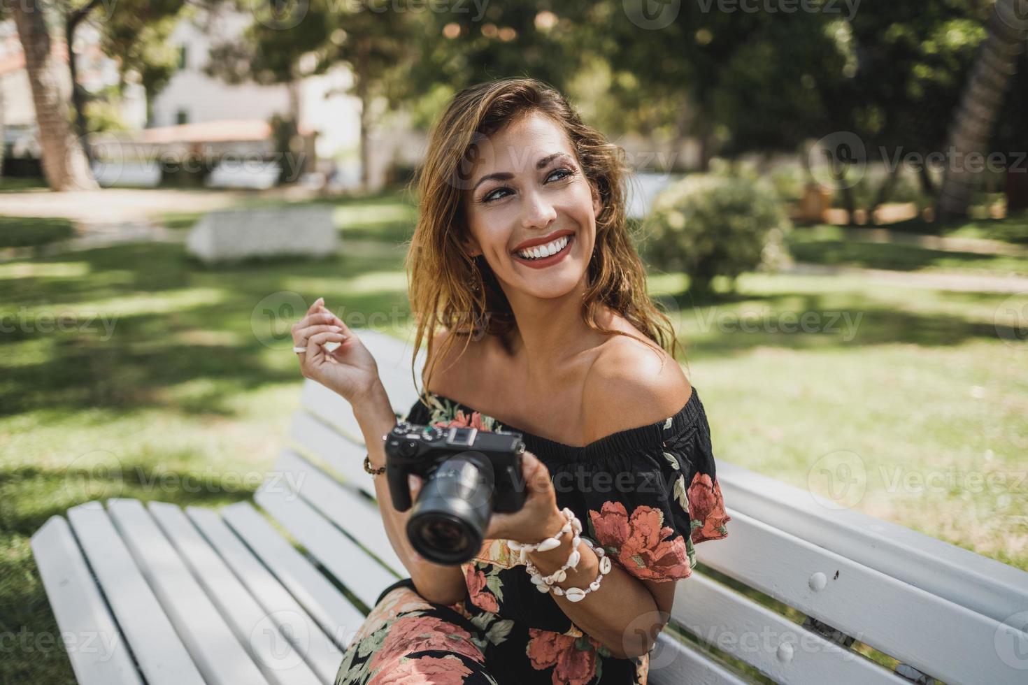 donna con digitale telecamera seduta su il panchina nel il parco foto