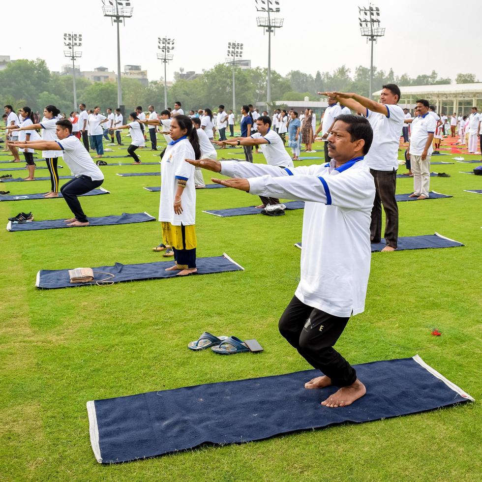 nuovo delhi, India, giugno 21 2022 - gruppo yoga esercizio sessione per persone a yamuna gli sport complesso nel delhi su internazionale yoga giorno, grande gruppo di adulti frequentando yoga classe nel cricket stadio foto