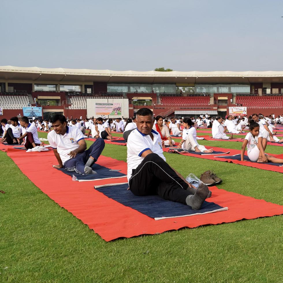 nuovo delhi, India, giugno 21 2022 - gruppo yoga esercizio sessione per persone a yamuna gli sport complesso nel delhi su internazionale yoga giorno, grande gruppo di adulti frequentando yoga classe nel cricket stadio foto