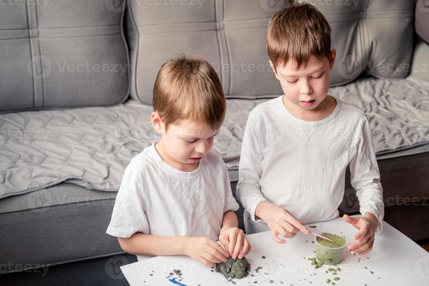 bambini giocare con cinetico sabbia a casa. sviluppo di bene il motore abilità. sabbia anti stress per bambini. Giochi quello calma il nervoso sistema. colorato sabbia per Giochi foto