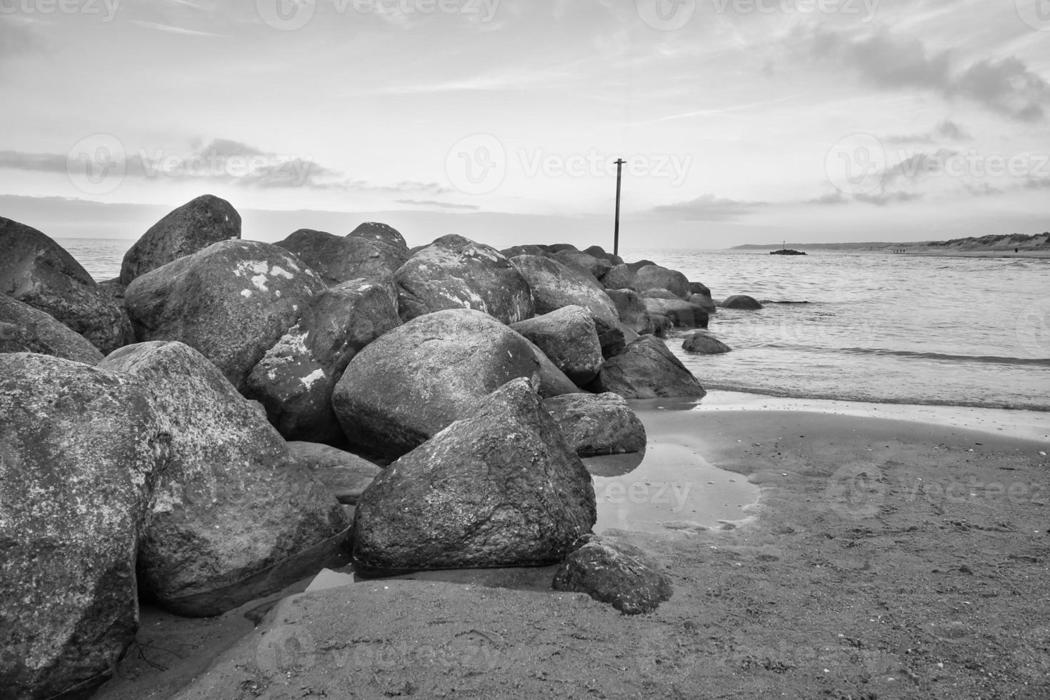 pietra frangiflutti sporge su in il acqua via il costa nel Danimarca. nero e bianca tiro foto
