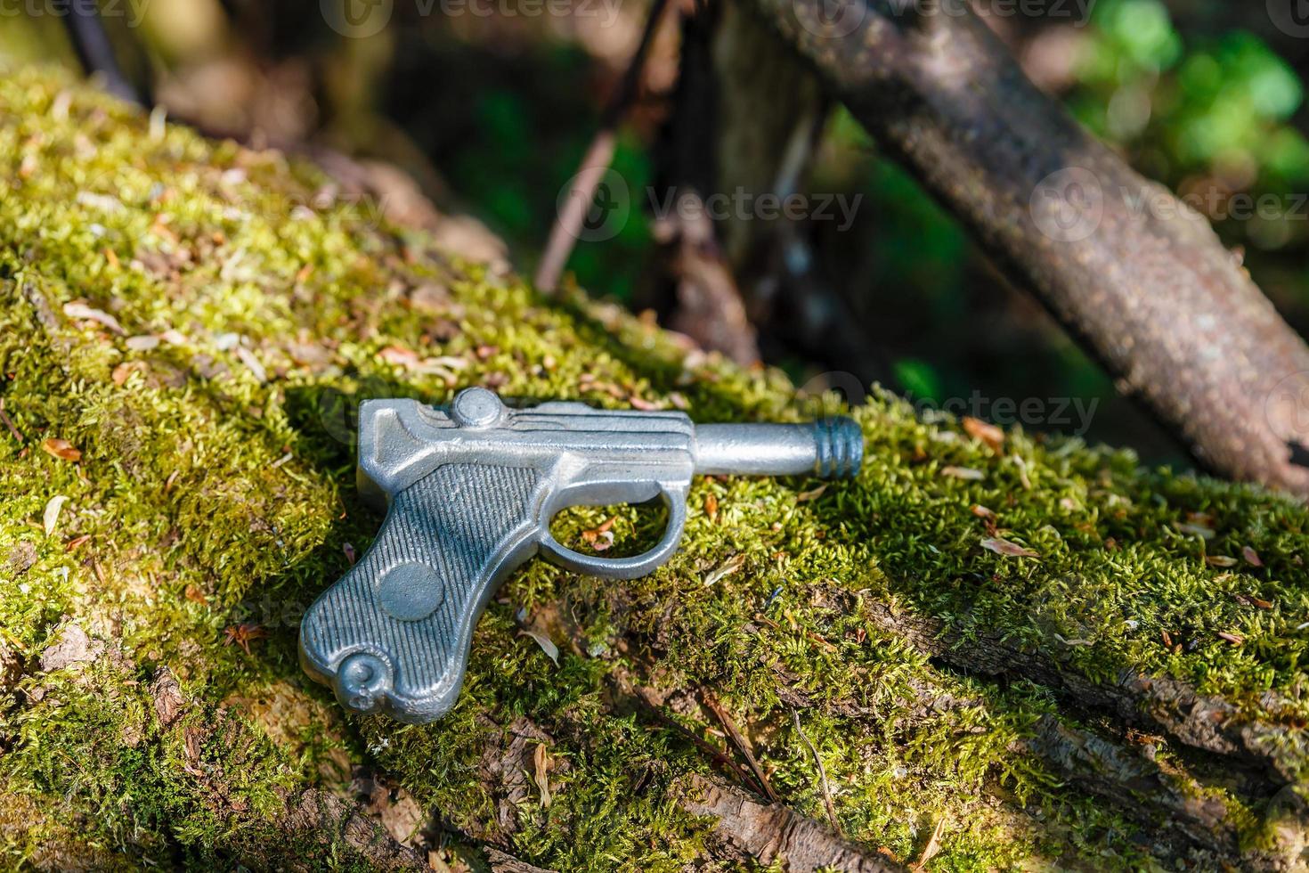 giocattolo pistola, giocattolo pistola fatto di condurre bugie su un vecchio albero con muschio. foto