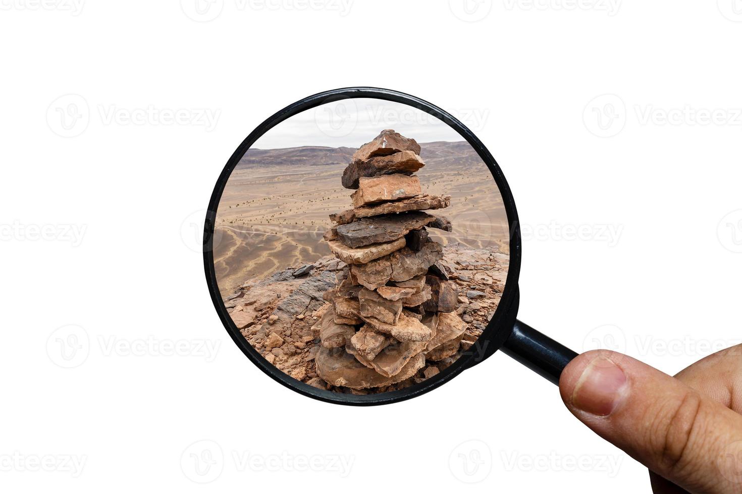 pietra mucchio marchio su il montagna picco, Visualizza attraverso un' ingrandimento bicchiere, bianca sfondo, ingrandimento bicchiere nel mano foto