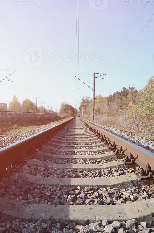 autunno industriale paesaggio. ferrovia sfuggente in il distanza tra verde e giallo autunno alberi foto