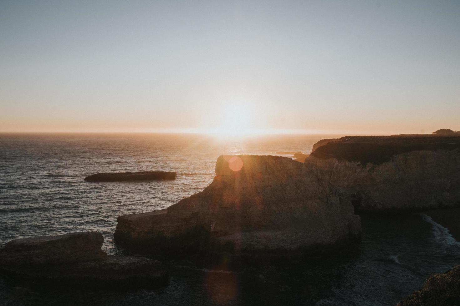 tramonto su rocce e scogliere accanto al mare foto