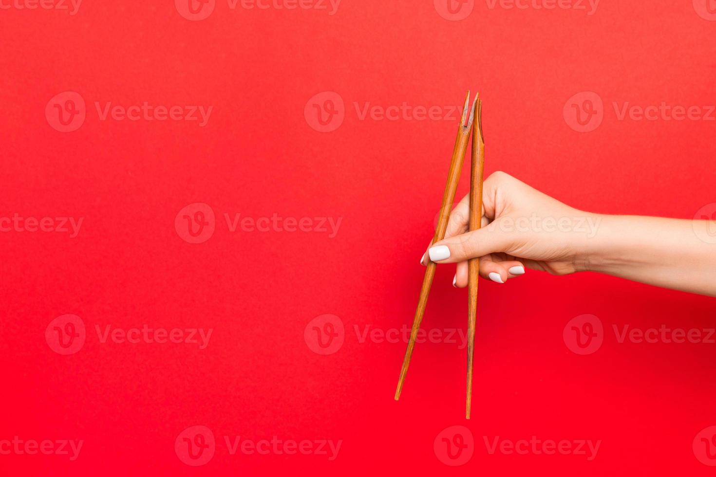 di legno bastoncini trattenuto con femmina mani su rosso sfondo. pronto per mangiare concetti con vuoto spazio foto