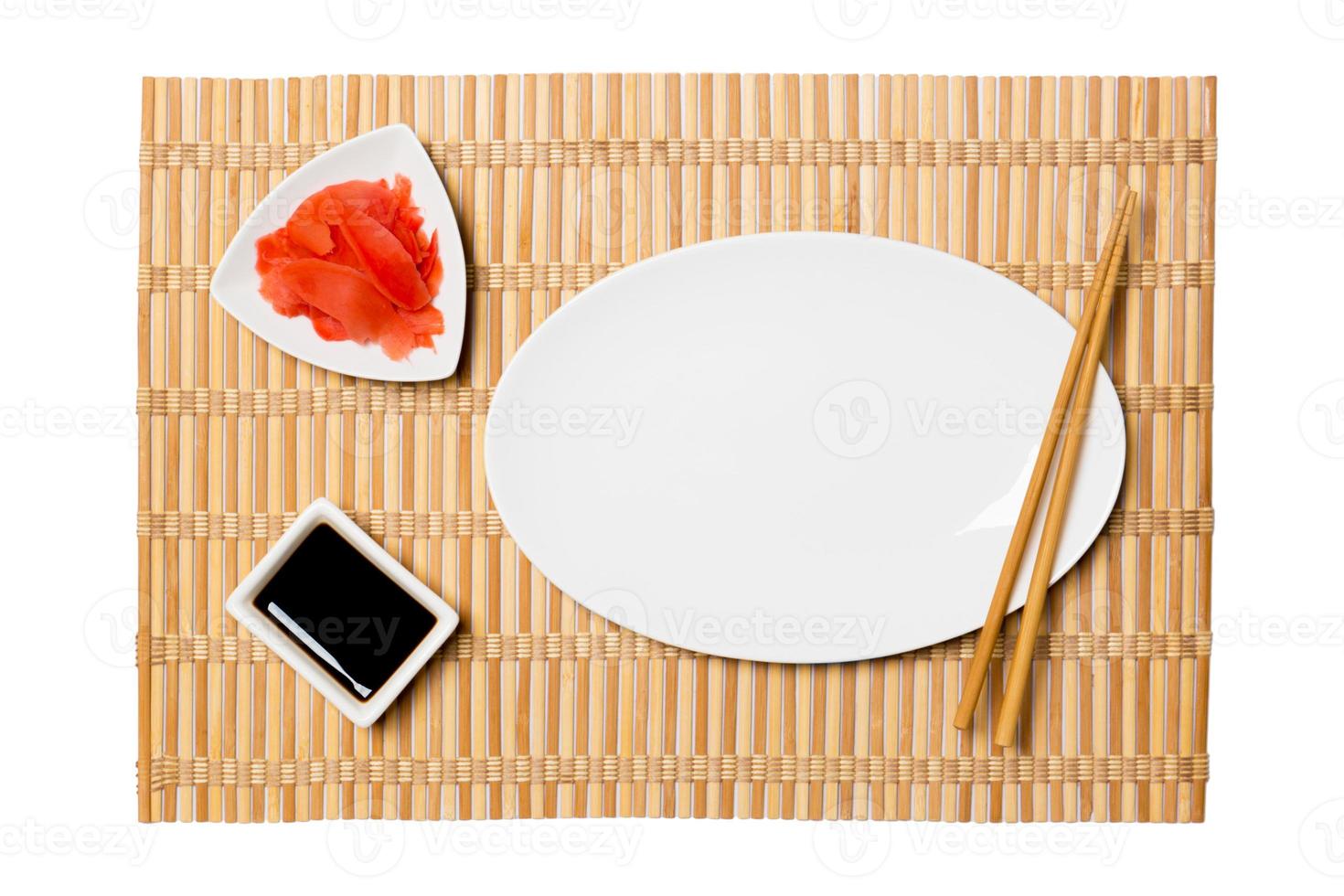 vuoto ovale bianca piatto con bastoncini per Sushi, Zenzero e soia salsa su giallo bambù stuoia sfondo. superiore Visualizza con copia spazio per voi design foto