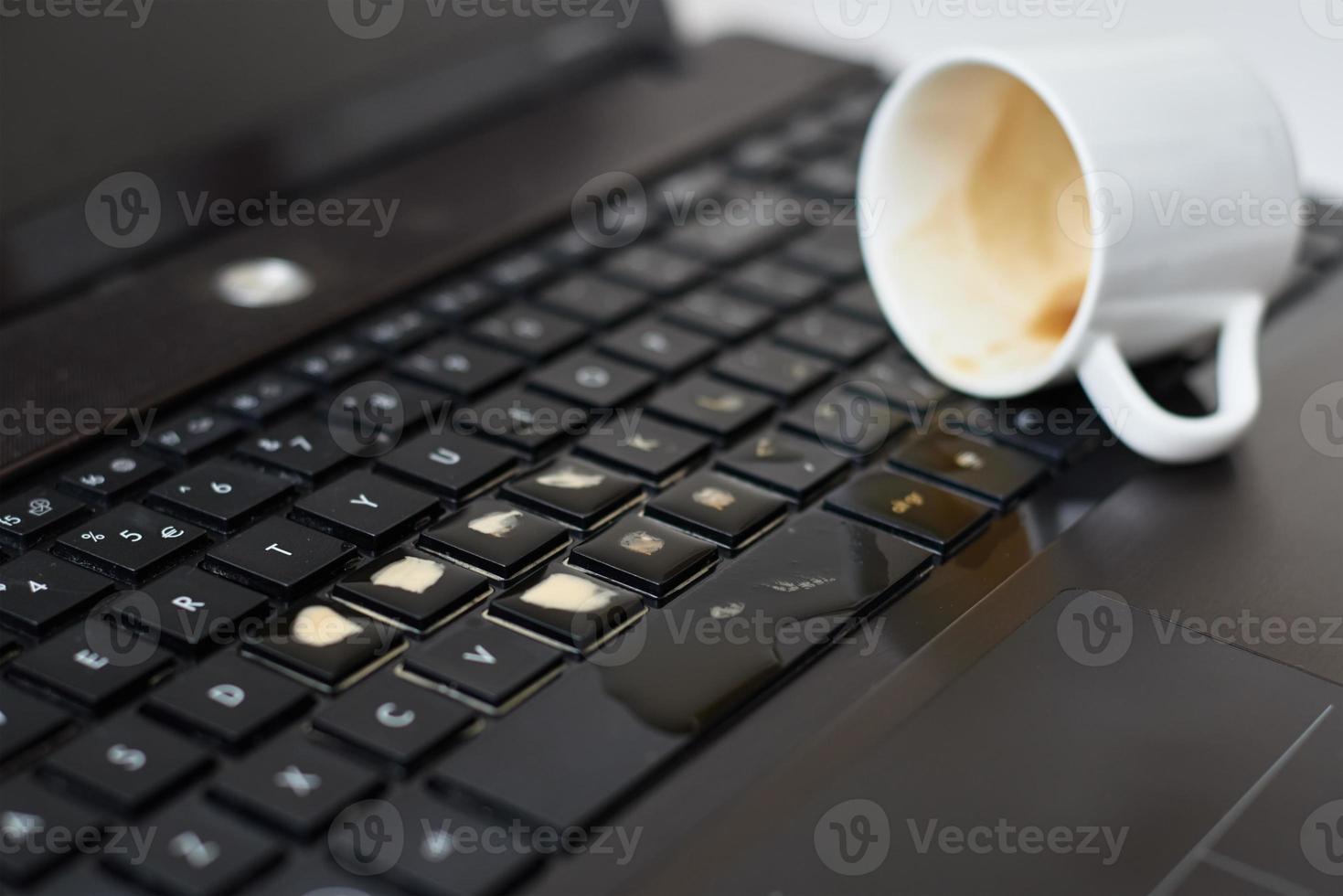 versare caffè a partire dal bianca tazza su il computer il computer portatile tastiera liquido foto