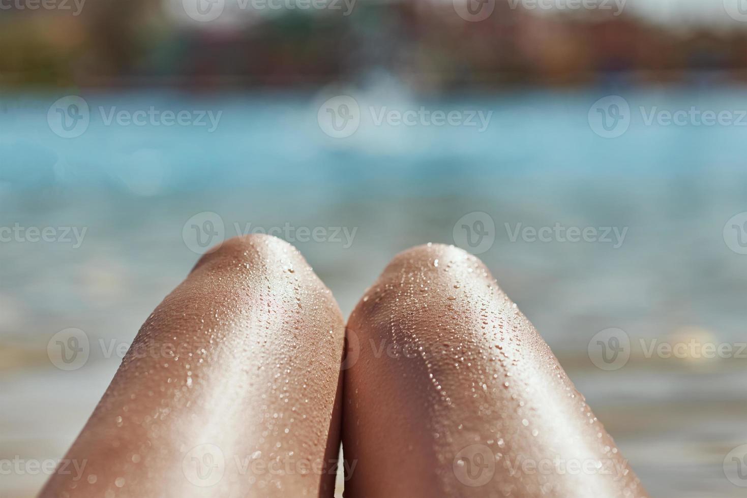 femmina gambe contro acqua piscina sfondo, avvicinamento foto