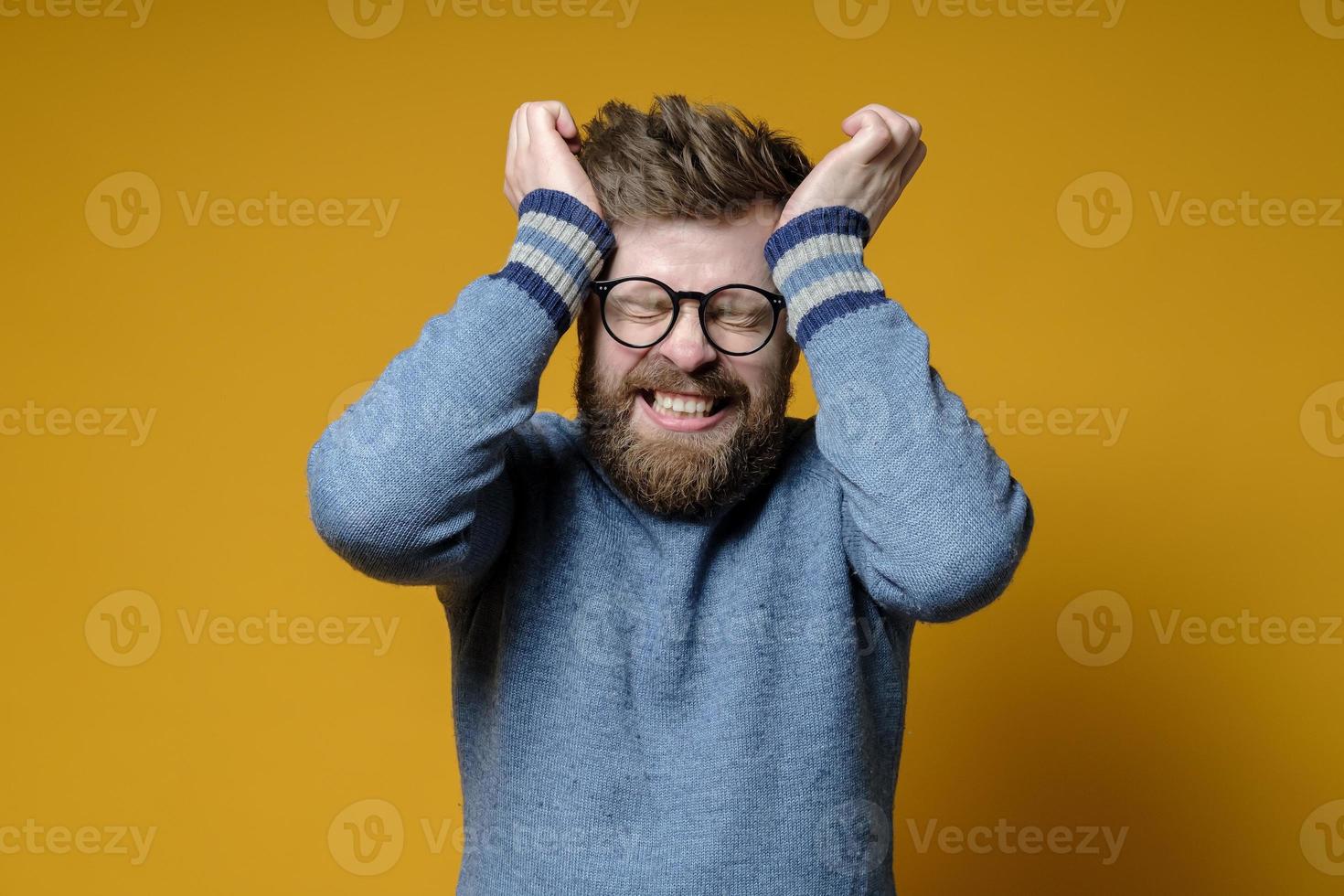 ispido uomo è stressato o ha un' acuto male alla testa, lui chiuso occhi e Bares denti, Tenere testa con mani. foto