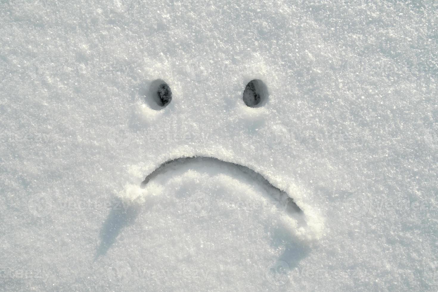 triste smiley viso disegnato nel il neve su un' soleggiato inverno giorno. copia spazio. negativo emozioni. foto