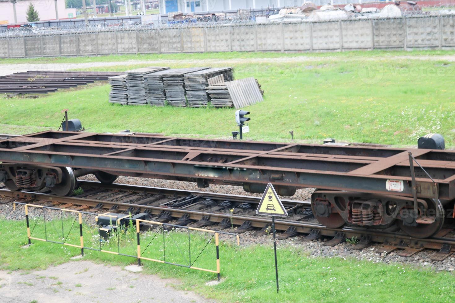 arrugginito vuoto metallo ferro su ruote nolo auto per il treno, locomotiva per il carrozza di merce lungo il rotaie a il ferrovia stazione foto