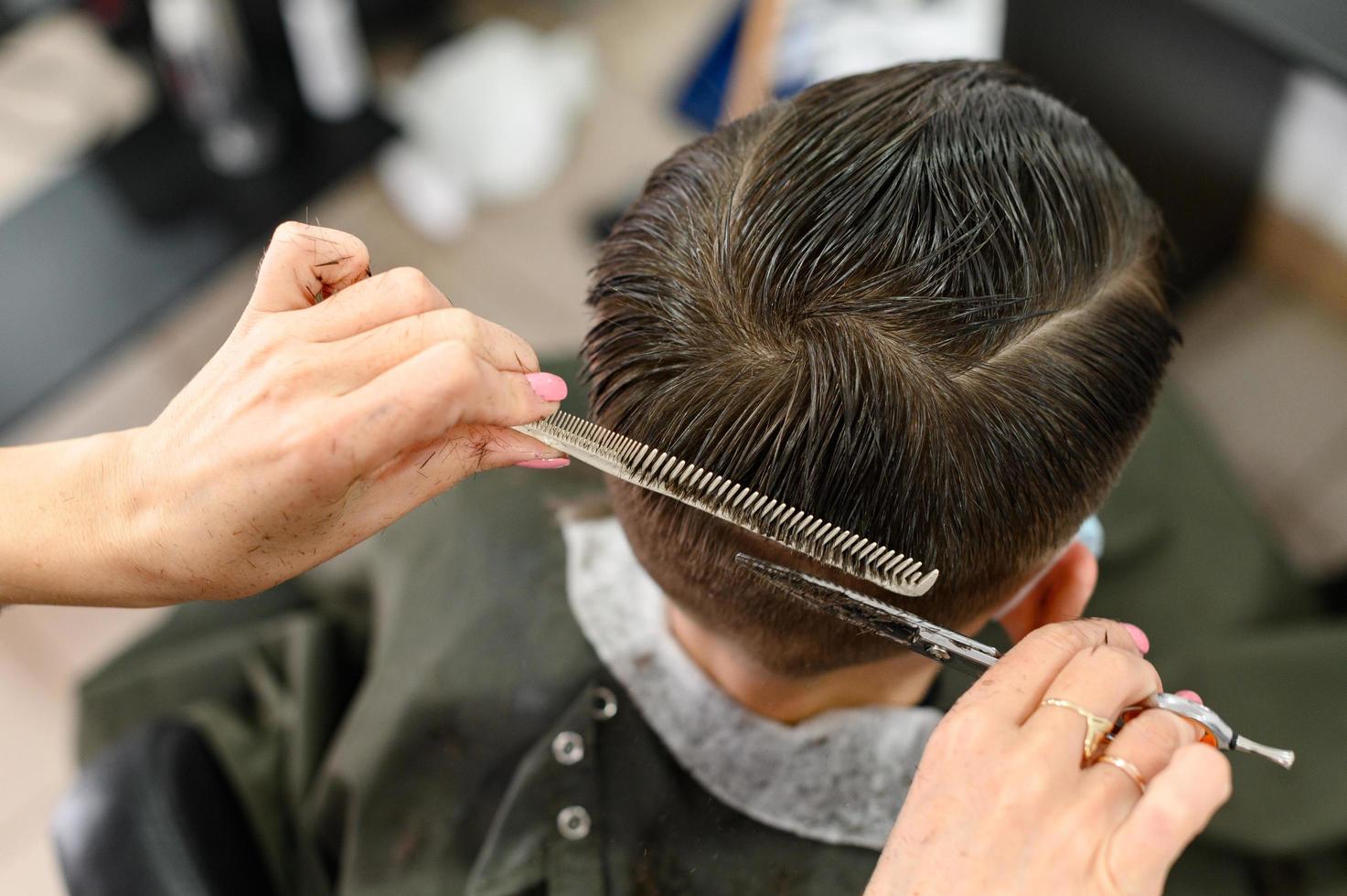 ragazzo adolescente si taglia i capelli durante una pandemia dal barbiere, si taglia i capelli e si asciuga i capelli dopo un taglio di capelli. foto