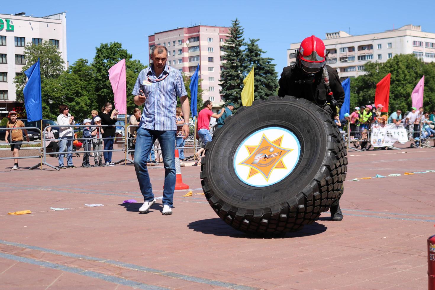 un' vigile del fuoco nel un' ignifugo completo da uomo e un' casco corre e giri un' grande gomma da cancellare ruota nel un' fuoco combattente concorrenza, bielorussia, Minsk, 08.08.2018 foto