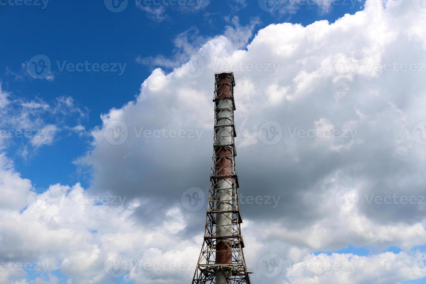 un' grande alto non ecologico metallico ferro tubo per il emissione di Fumo gas a il prodotto petrochimico chimico raffineria industriale raffineria contro il sfondo di il blu cielo foto