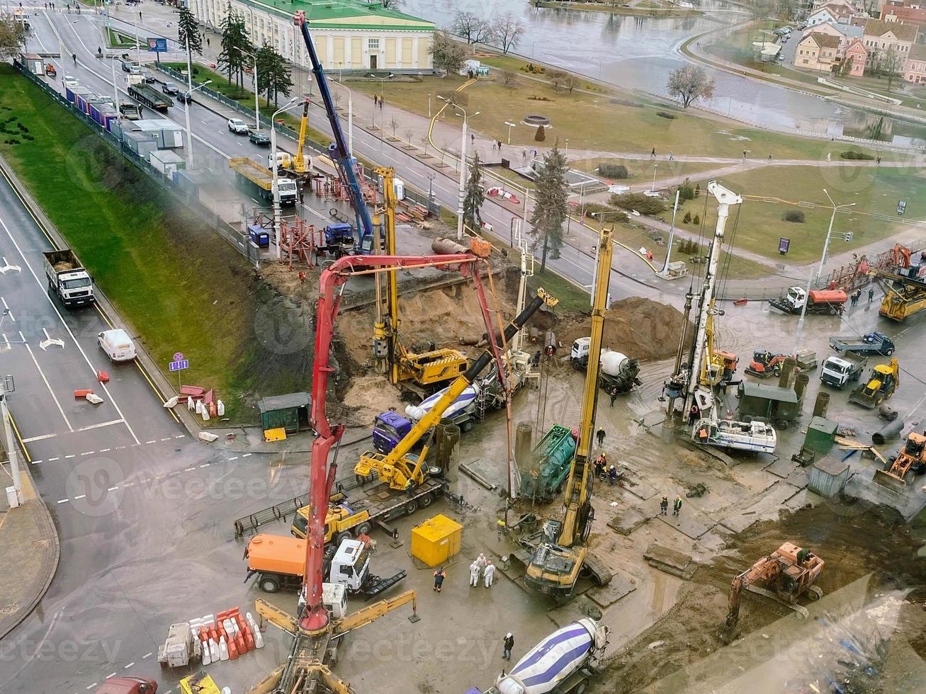 Visualizza a partire dal un' altezza di un' grande costruzione luogo. costruzione di un cavalcavia nel il città centro durante il pioggia. su luogo costruzione macchinari e gru foto