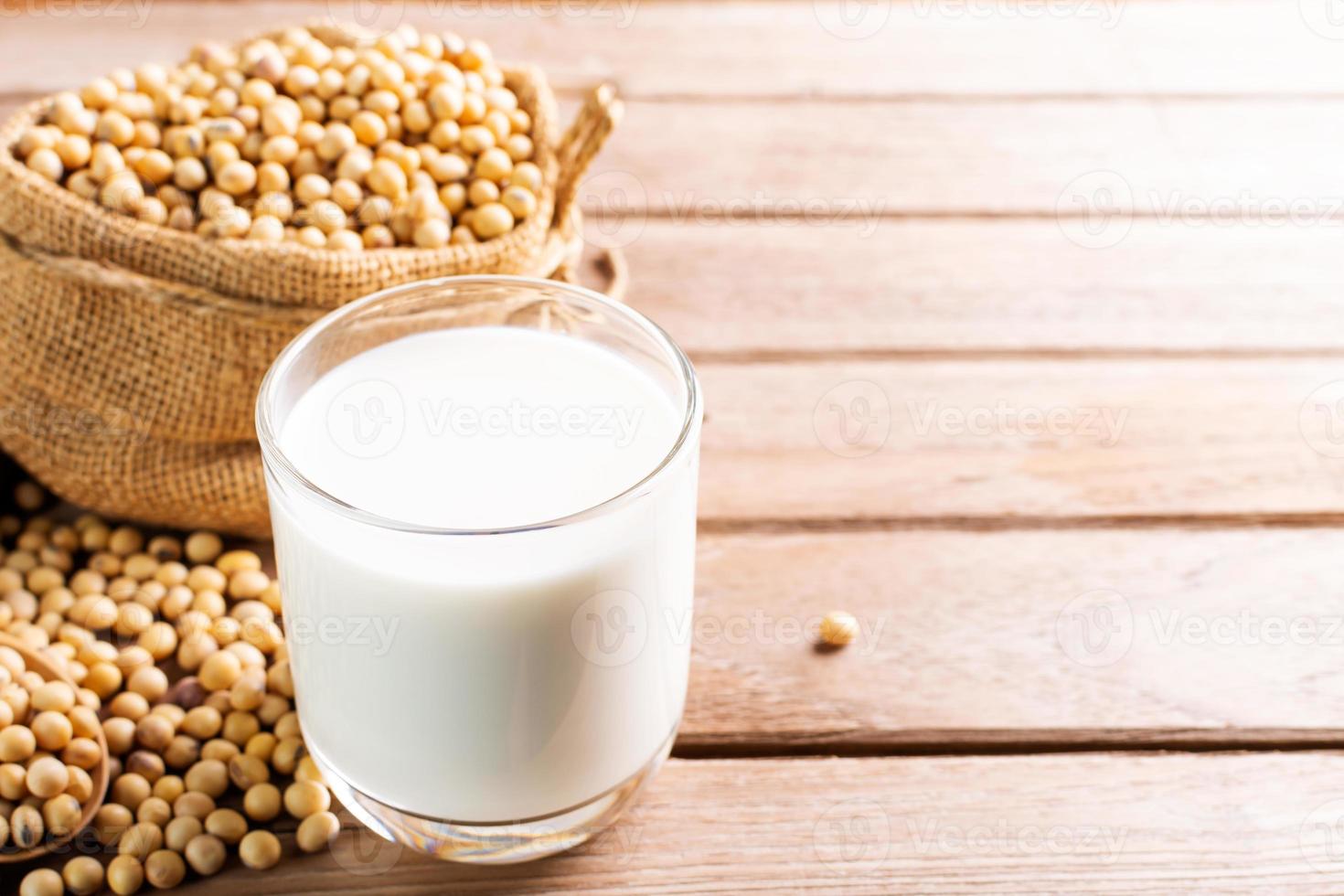 soia latte nel un' bicchiere con semi di soia su un' di legno tavolo biologico colazione, alto proteina, sano, agricolo prodotti, vegetariano foto