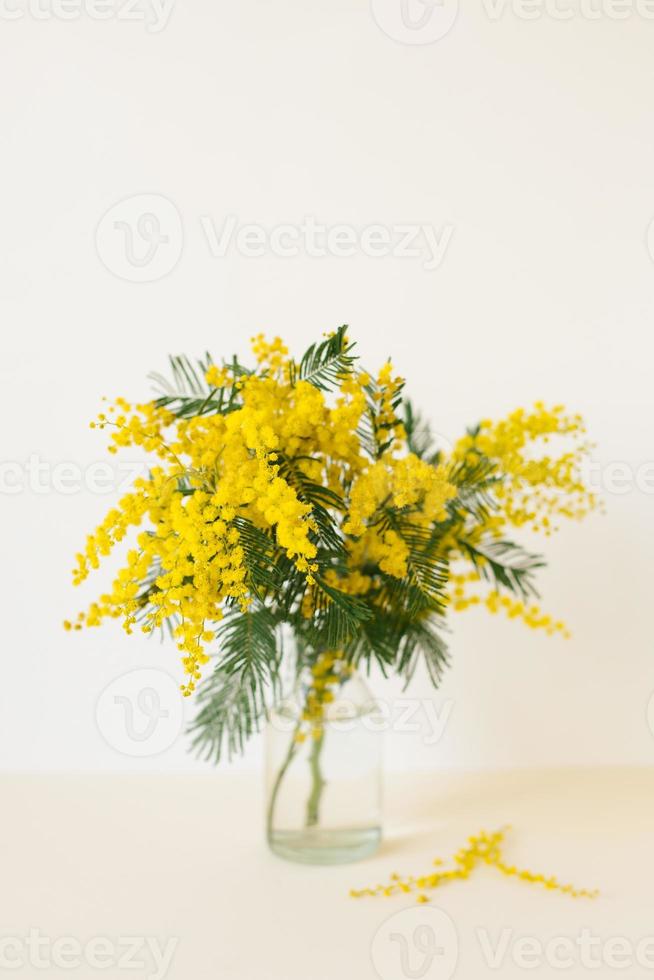 un' mazzo di giallo mimosa fiori nel un' bicchiere vaso. il concetto di Da donna primavera o La madre di giorno. saluto carta con copia spazio foto