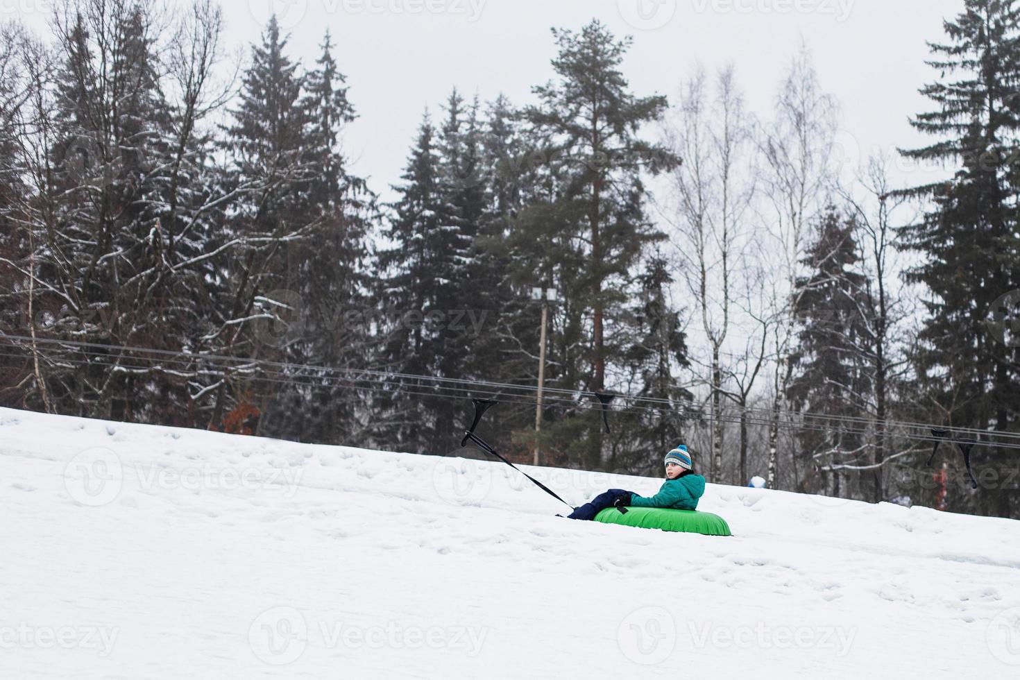 bambino avendo divertimento su neve tubo. ragazzo è equitazione un' tubo. inverno intrattenimento. ragazzo scorrevole discesa su tubo. cavalcata un' sollevamento foto