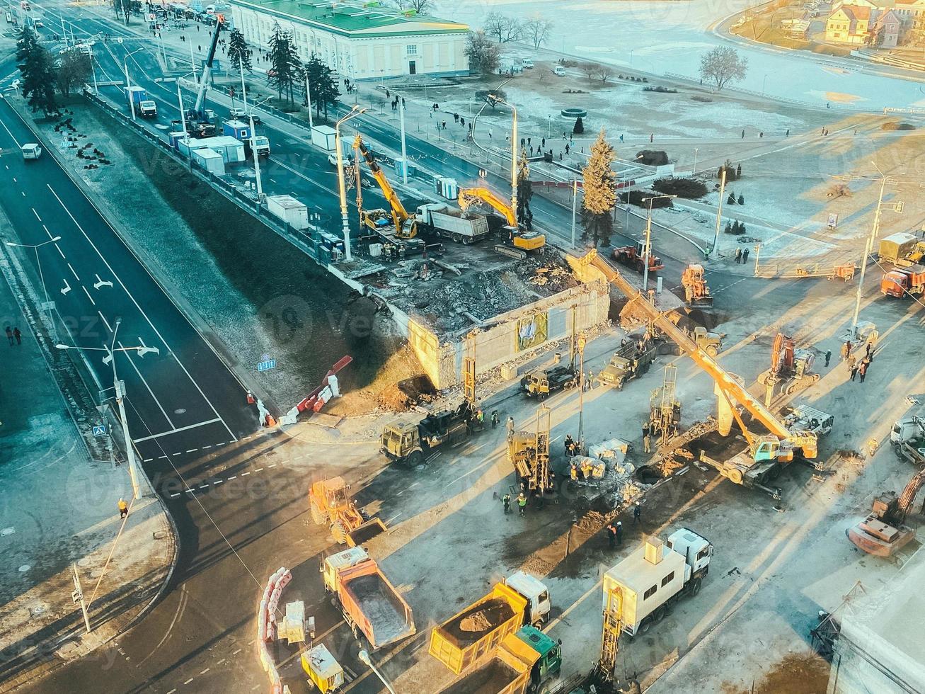 costruzione di un' nuovo cavalcavia nel il città centro su un' nevoso strada. strada riparazione, costruzione di un' ponte con costruzione attrezzatura, enorme giallo gru foto