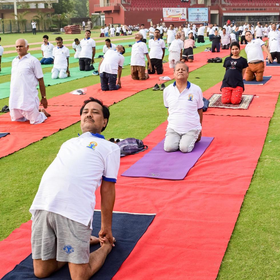 nuovo delhi, India, giugno 21 2022 - gruppo yoga esercizio sessione per persone a yamuna gli sport complesso nel delhi su internazionale yoga giorno, grande gruppo di adulti frequentando yoga classe nel cricket stadio foto