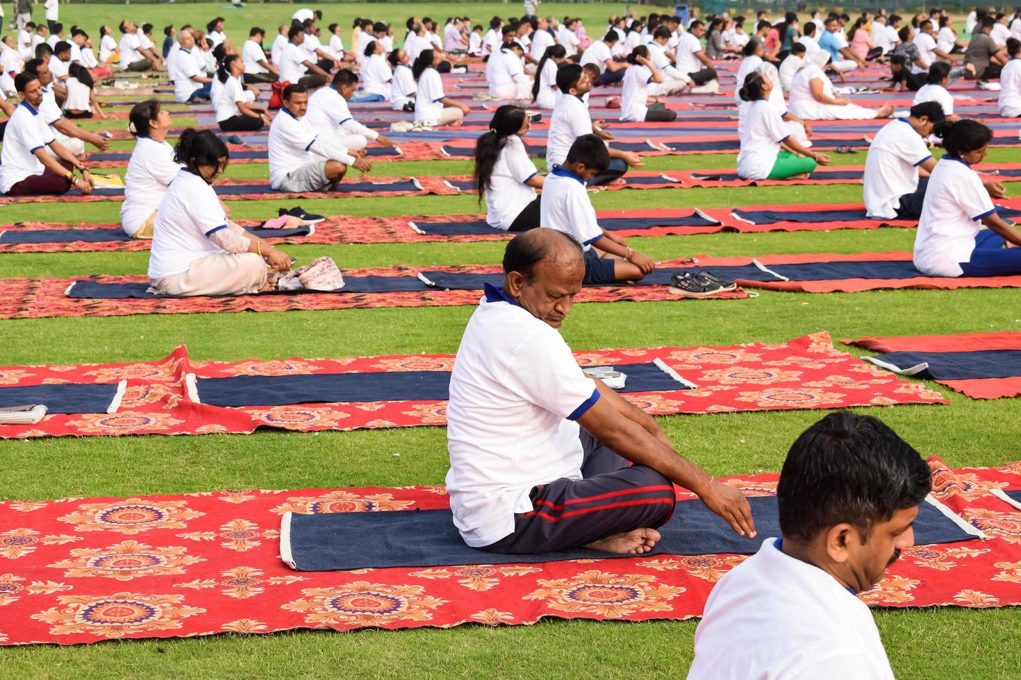 nuovo delhi, India, giugno 21 2022 - gruppo yoga esercizio sessione per persone a yamuna gli sport complesso nel delhi su internazionale yoga giorno, grande gruppo di adulti frequentando yoga classe nel cricket stadio foto