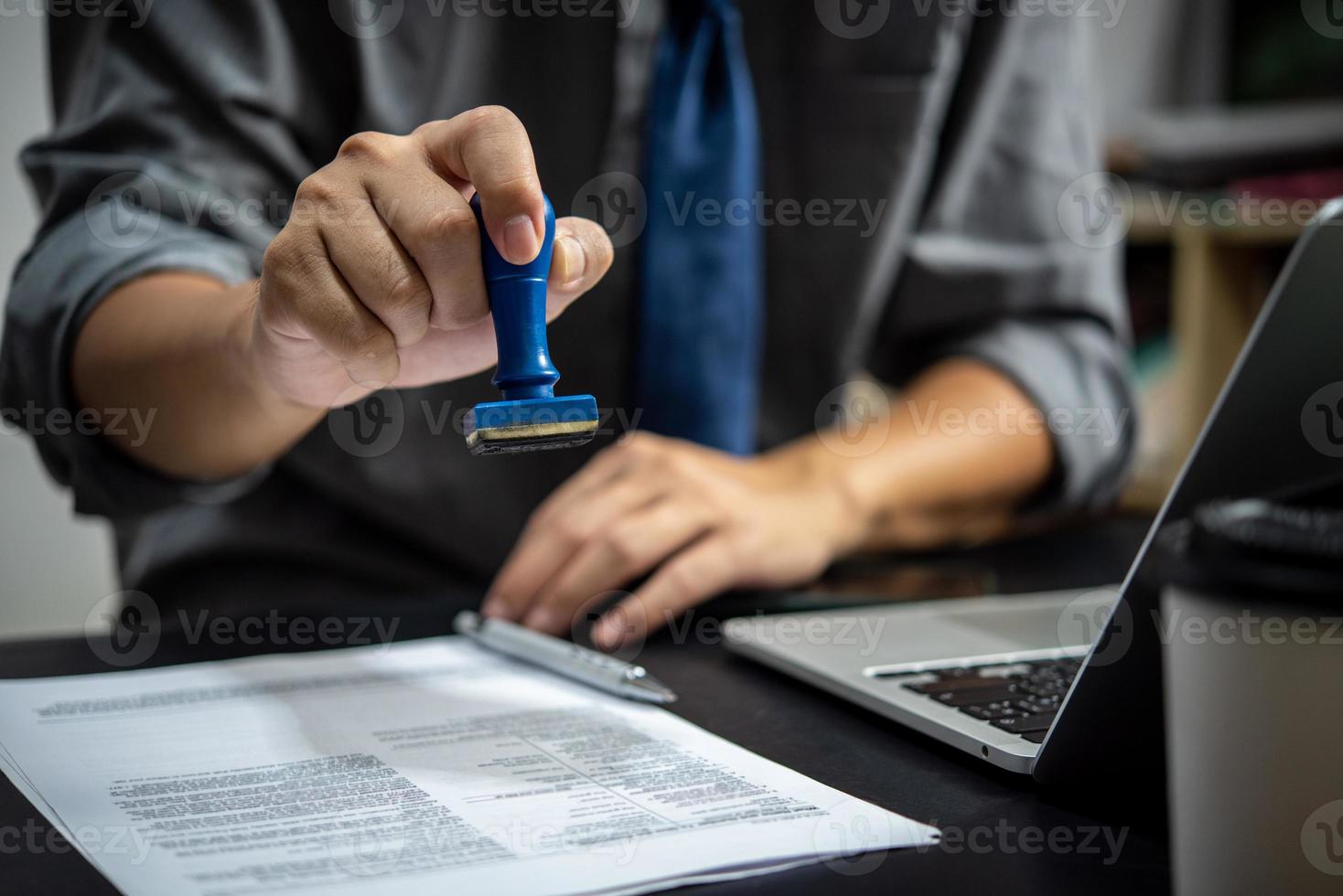 uomo d'affari mano stampaggio approvato su certificato documento contrarre nel ufficio. avvocato stampaggio permesso su lavoro d'ufficio a di legno scrivania. foto