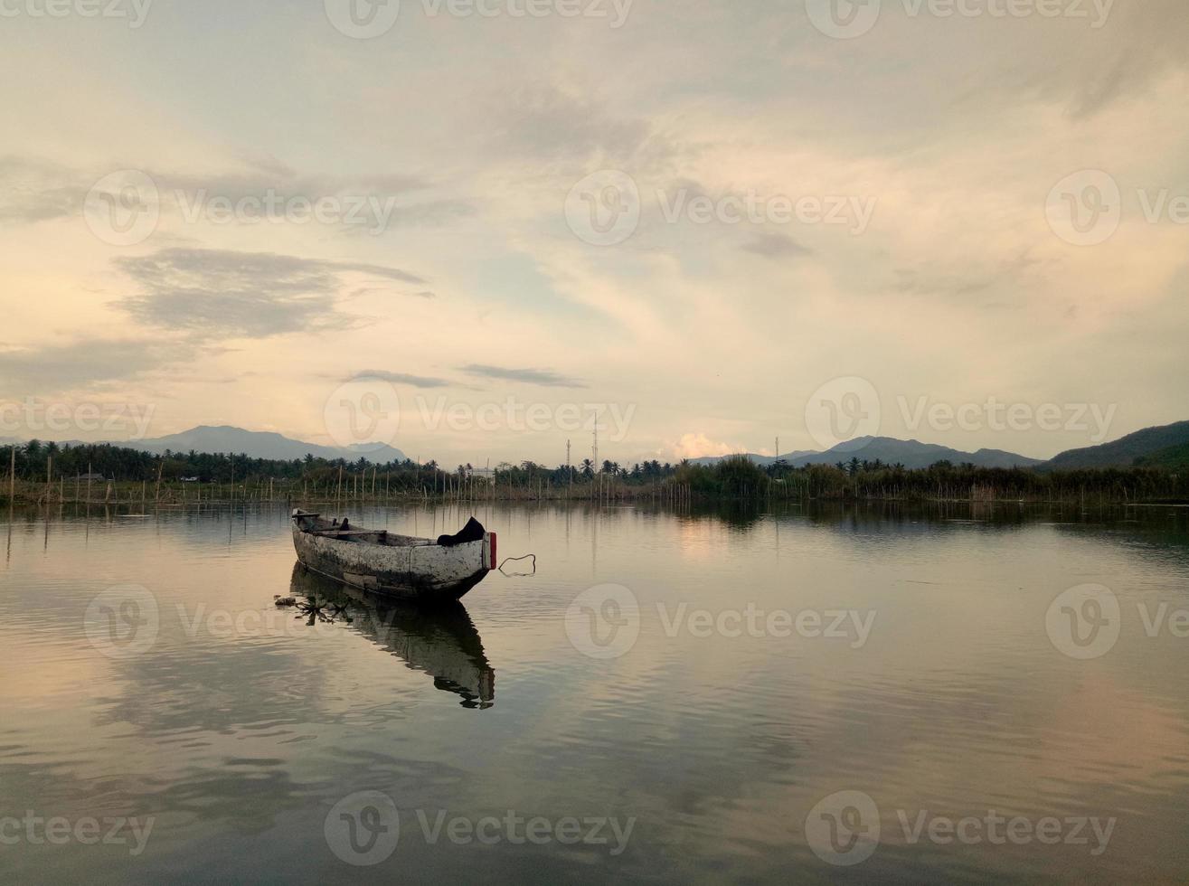 tradizionale di legno barca galleggiante su il acque di lago limbo, gorontalo, Indonesia. piccolo di legno barca a remi su un' calma lago foto