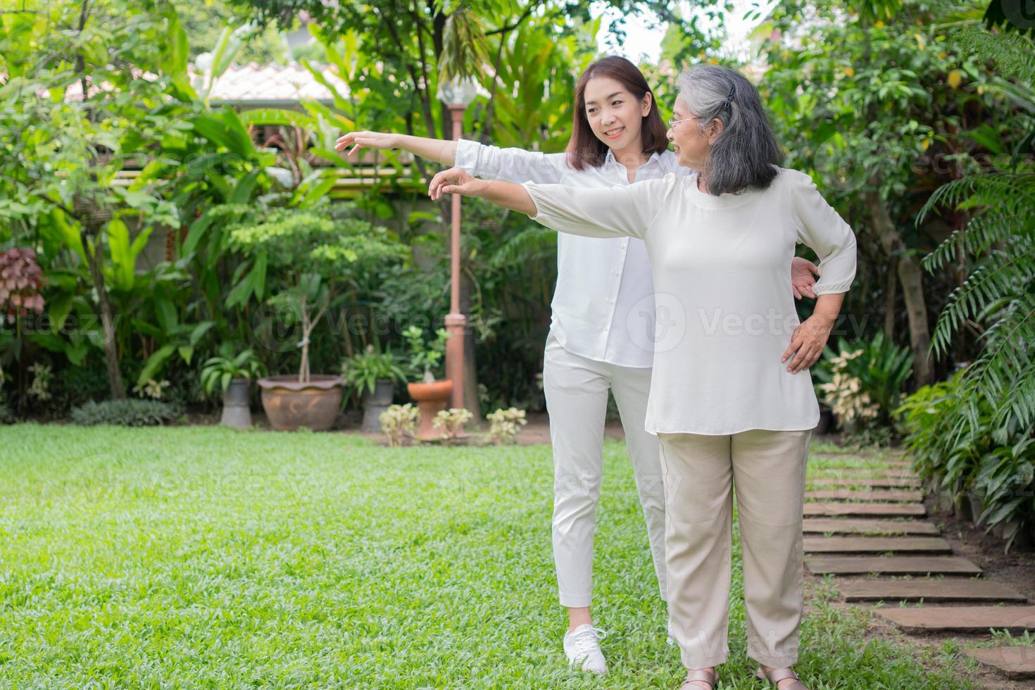 un'anziana anziana donna asiatica e fare esercizio in cortile con sua figlia. concetto di felice pensionamento con la cura di un caregiver e risparmi e assicurazione sanitaria senior, famiglia felice foto