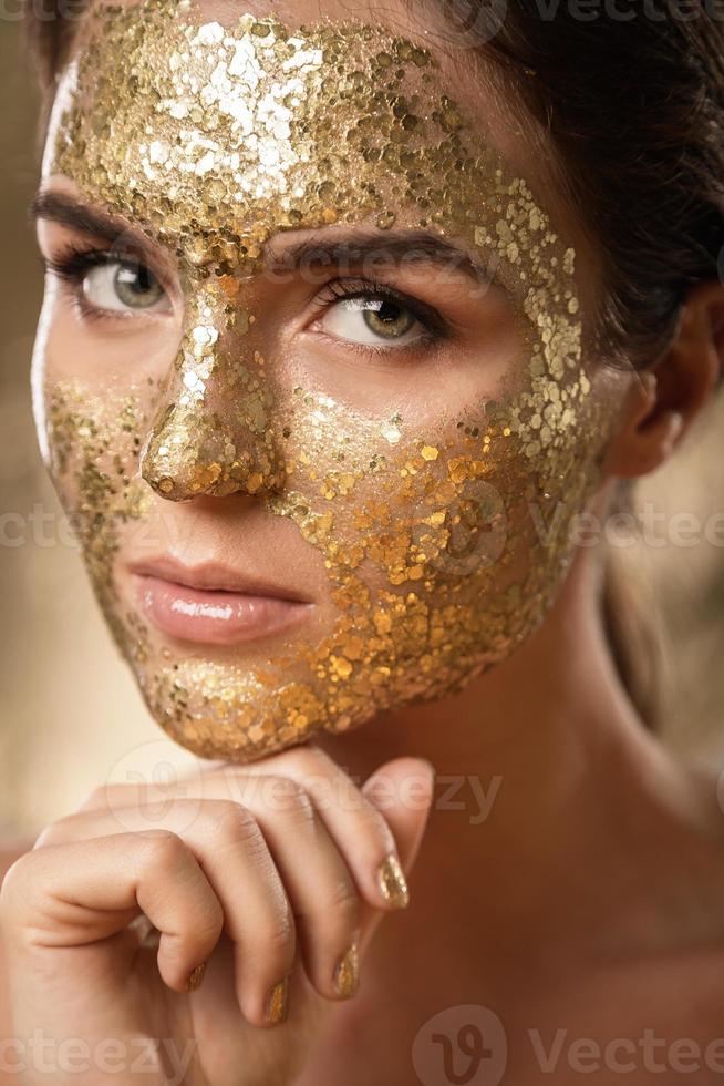 bellissimo donna con d'oro splendente maschera su sua viso per pelle trattamento foto