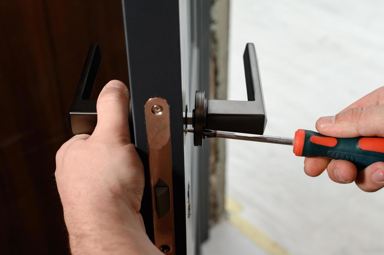 un' uomo installa un' maniglia nel un' porta, carpenteria a casa. foto