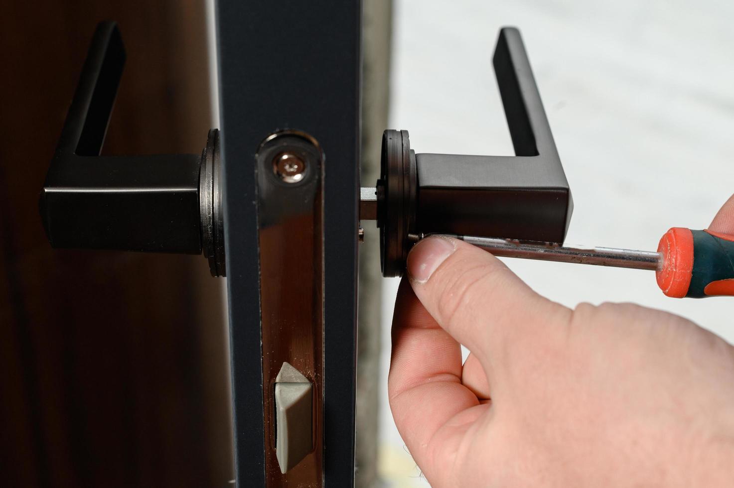 un' uomo installa un' maniglia nel un' porta, carpenteria a casa. foto