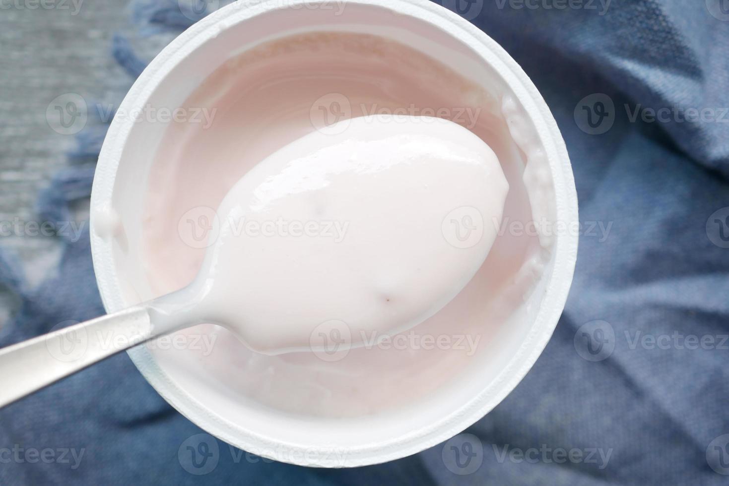 cucchiaio raccogliere fresco Yogurt nel un' ciotola su tavolo foto