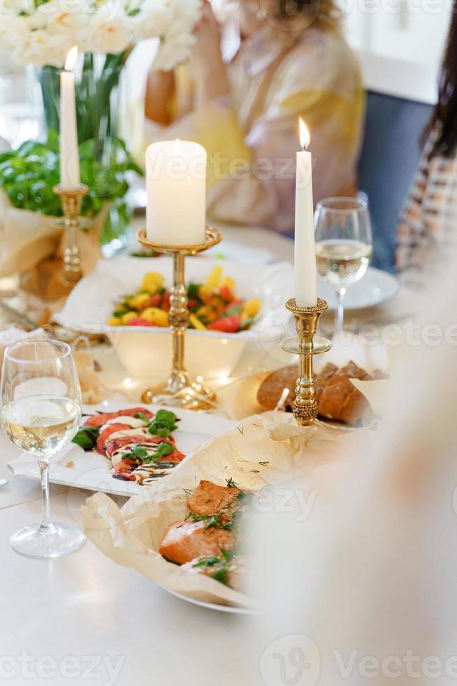 festivo tavolo con cibo, vino, fiori e candele. foto