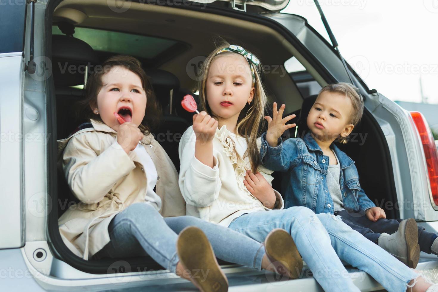 poco bambini seduta nel un' macchine tronco prima un' strada viaggio foto